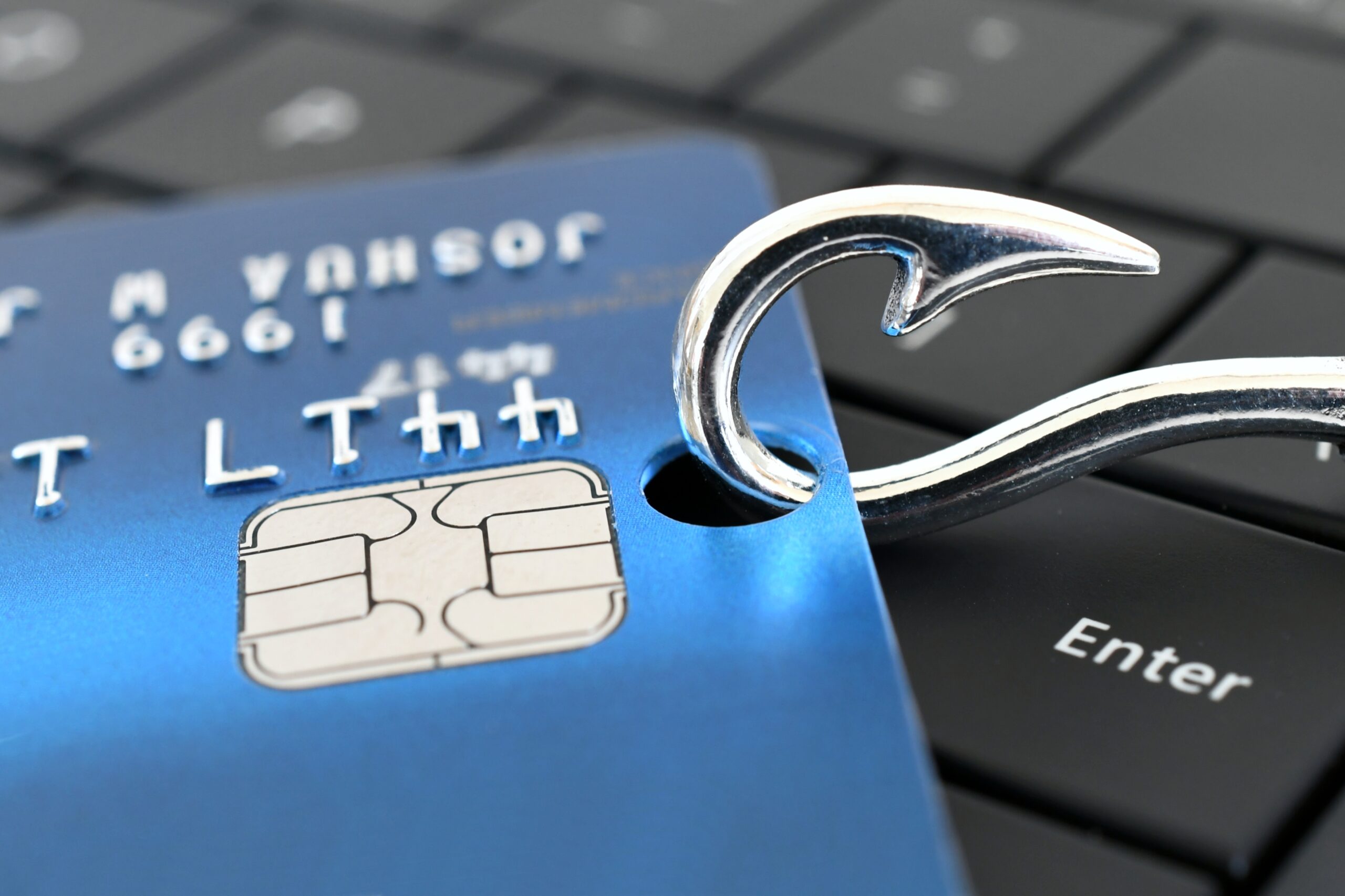 Phishing Tarjeta de crédito encanchada con un anzuelo sobre un teclado de computadora